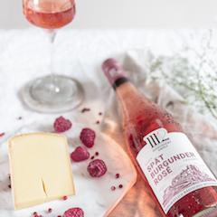 Ein elegantes Arrangement mit einer Flasche Spätburgunder Rosé, einem Glas Wein und Käse auf einem marmorierten Untergrund.