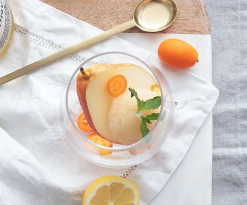 Ein elegantes Dessertglas gefüllt mit einer erfrischenden Sorbet-Mischung aus Birne und Zitrusfrüchten, garniert mit Minze.