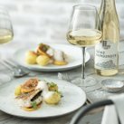 Ein elegantes Gericht mit gebratenem Fisch, Kartoffeln und Zitronenscheiben, serviert auf einem weißen Teller.