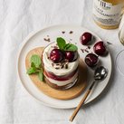 Ein köstliches Dessert in einem Glas, geschichtet mit Sahne, Kirschen und Schokoladenstückchen, garniert mit frischer Minze.