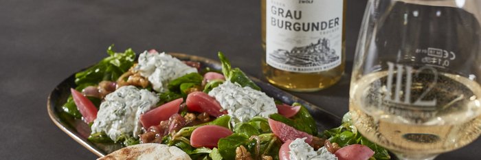 Ein gedeckter Tisch mit einem gesunden Salat, Fladenbrot und einer Flasche Grau Burgunder, ideal für ein entspanntes Essen.