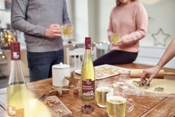 Die gemütliche Atmosphäre zeigt Freunde, die zusammen Plätzchen backen und Glühwein in der Hand halten.
