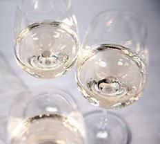 Ein Trio von Weingläsern, gefüllt mit funkelndem Wein, steht auf einem Tisch und schafft eine festliche Atmosphäre.